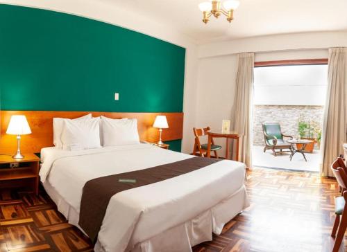 塔克纳Dorado Hotel Boutique - Tacna的一间卧室设有一张大床和绿色的墙壁