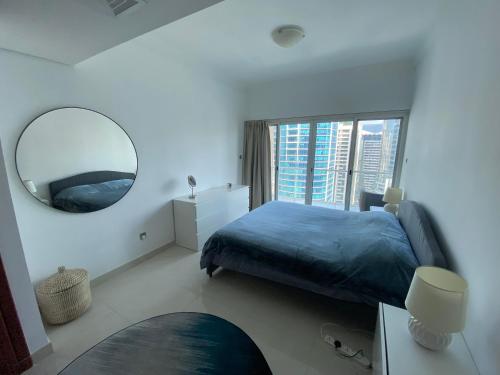 迪拜One bedroom apartment with pool & gym near Marina的一间卧室配有蓝色的床和镜子