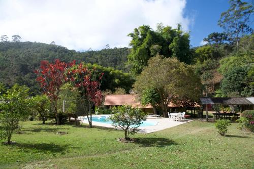 新弗里堡Casa em Friburgo com piscina lareira suíte & quarto的一座有树木和房子的院子内的游泳池