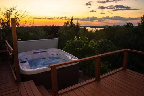 RoseneathCozy Sunset Cottage Overlooking Rice Lake的甲板上的热水浴池,享有日落美景