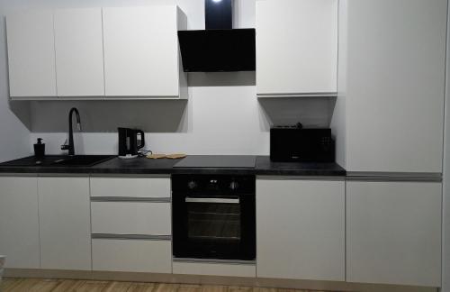 库特诺Apartament Różana Piątka的厨房配有白色橱柜和黑烤箱。