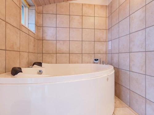 博恩瑟6 person holiday home in Bogense的浴室设有白色浴缸,浴室设有瓷砖墙壁。