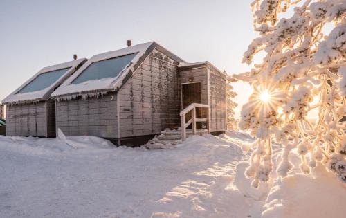 萨利色尔卡Aurora Collection的一座被雪覆盖的建筑,在背后是太阳