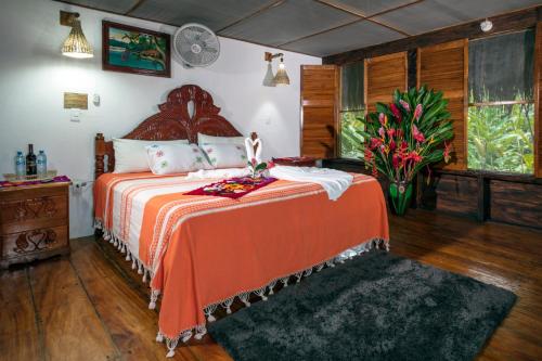 Tlatizapán恰帕斯塞尔瓦拉坎多纳拉斯瓜卡马亚斯山林小屋的一间卧室配有一张带橙色床罩和鲜花的床。