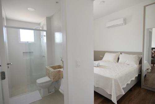 邦比尼亚斯Vila do Centro Apart Hotel的白色的浴室设有一张床和淋浴。