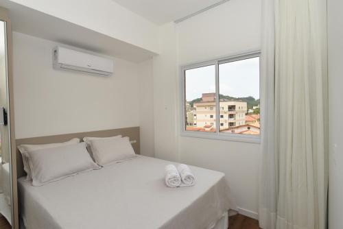 邦比尼亚斯Vila do Centro Apart Hotel的白色的卧室设有床和窗户