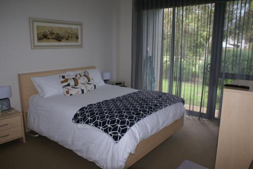 托基Torquay Golf Retreats - Pool, Beach, Tennis, Golf的一间卧室设有一张床和一个大窗户