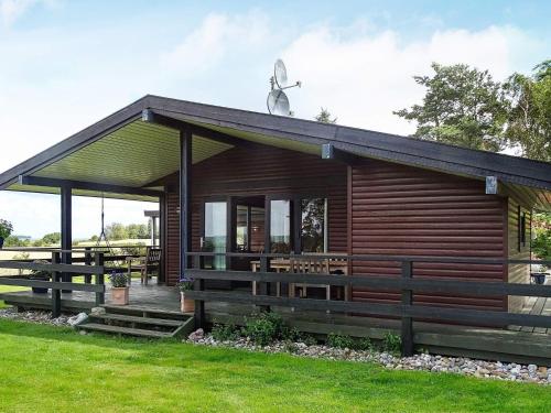 斯文堡8 person holiday home in Svendborg的小木屋设有门廊和草坪