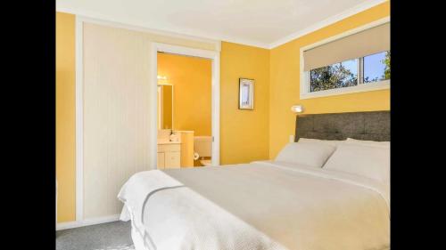 ComboyneOrange Blossom- Comboyne Mountain Cottages的卧室配有白色的床和镜子