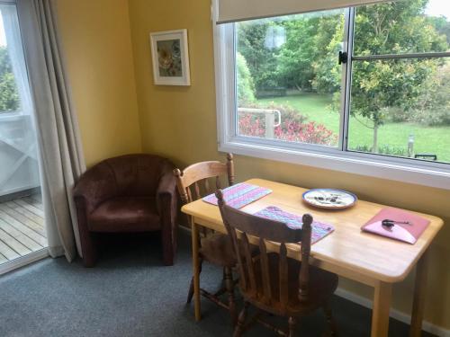 ComboyneOrange Blossom- Comboyne Mountain Cottages的一间带桌子和椅子的用餐室以及窗户。