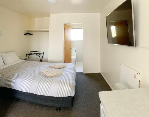 惠灵顿阿德莱德汽车旅馆的一间小卧室,配有一张床和镜子