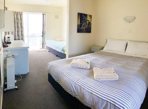 惠灵顿阿德莱德汽车旅馆的一间卧室配有一张大床和毛巾