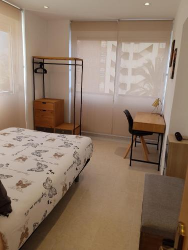 贝尼多姆HR PARADISE RESIDENCIAL LOIX的一间卧室配有一张床、一张桌子和一把椅子
