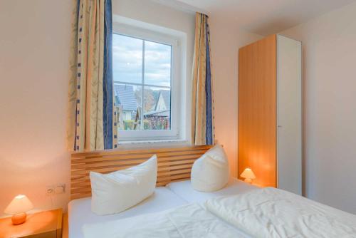 蒂索Strandhaus Thiessow Whg_ 1的卧室配有一张带两个枕头的床和窗户