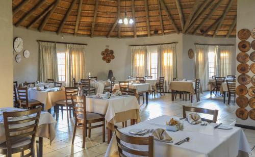 NongomaNongoma Lodge & Inn CC的一间设有白色桌椅和窗户的用餐室