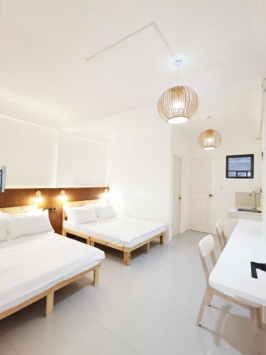 马尼拉NomadsMNL Hostel的一间设有两张床和一张桌子及椅子的房间