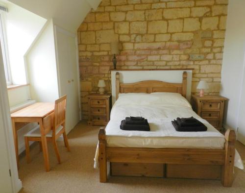 奇平卡姆登Cotswold Charm George Barn的一间卧室配有一张床、一张桌子和一张书桌