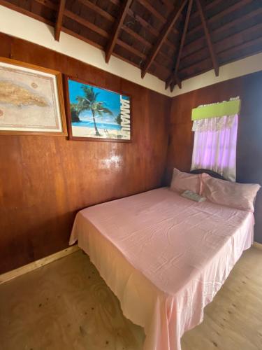 尼格瑞尔Westport Cottage的一间小卧室,卧室内配有粉红色的床