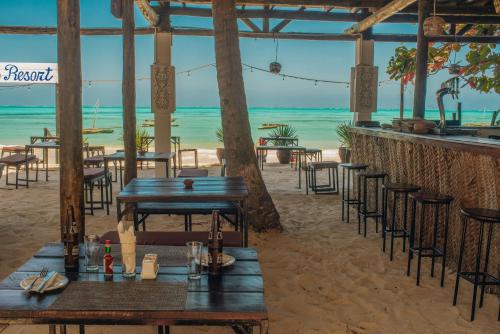 江比阿Dhow Resort的海滩上带桌椅的海滩酒吧