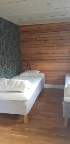 HammarstrandAmmeråns Fiskecamp的一间卧室设有两张床和木墙