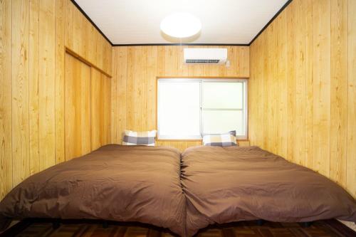 壹岐市I,K,I HOUSE TSURUKIFURE - Vacation STAY 14773v的木墙和窗户的客房内的一张床位