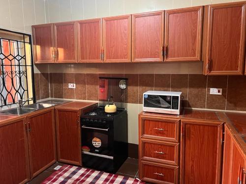 弗里敦Delornya Complex的厨房配有木制橱柜和炉灶上的微波炉