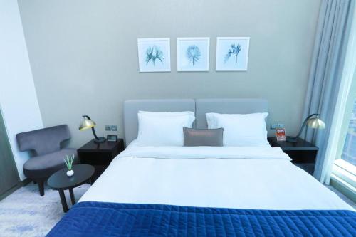 迪拜Damac Maison Prive Deluxe Studio with Burj-khalifa view的卧室配有一张白色大床和一把椅子