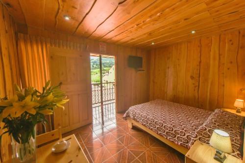 Poasito巴西烧烤餐厅酒店的木制客房内的一间卧室,配有一张床