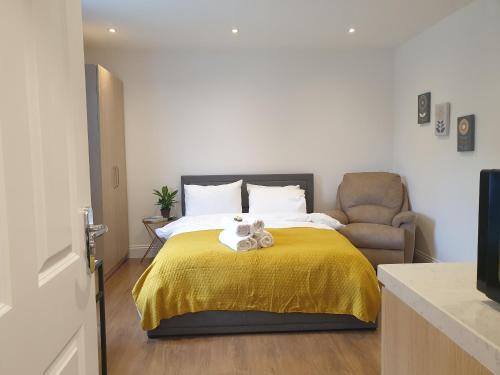 伦敦New - Spacious London 1 bedroom king bed apartment in quiet street near parks 1072gar的一间卧室配有一张带黄毯和椅子的床