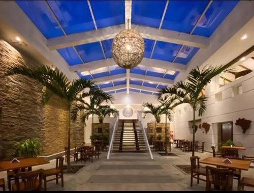 布希奥斯Hotel Búzios Resort com Entretenimento的餐厅拥有蓝色天花板,种植了棕榈树,设有桌子