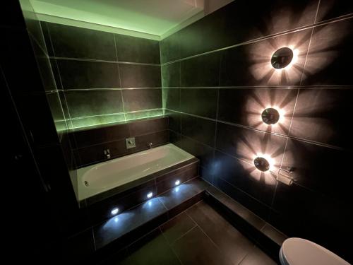 汉堡TruRetreats Design Loft I Riesige Küche I Wallbox I 65z SmartTV I 150qm的浴室配有浴缸和墙上的灯。