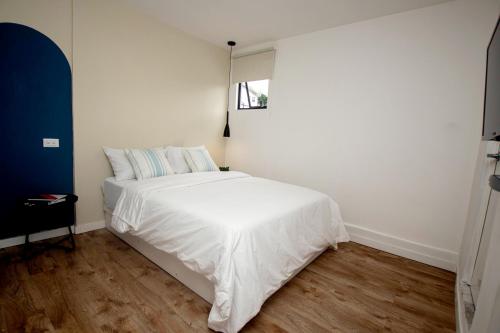 QuesadaHotel Ventura的卧室配有白色的床和窗户。
