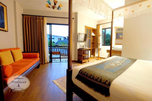 清迈乌莱萨拜迪住宿加早餐旅馆的一间卧室配有一张床和一张沙发,并设有一个阳台