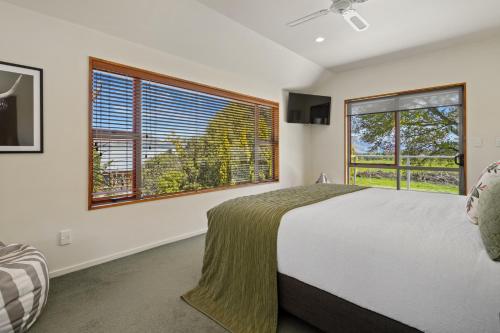 汉默温泉Welcome Home - Hanmer Springs Holiday Home的一间卧室设有一张大床和两个窗户。