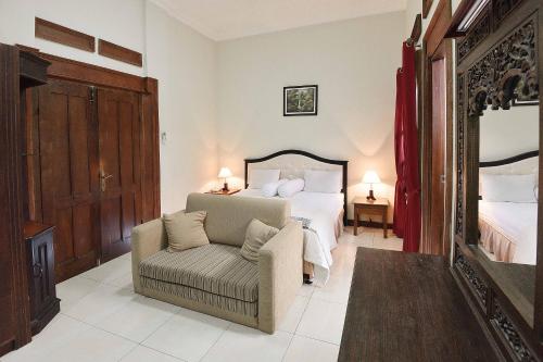 日惹Ndalem Maharani Guest House的一间卧室配有一张床、一把椅子和镜子