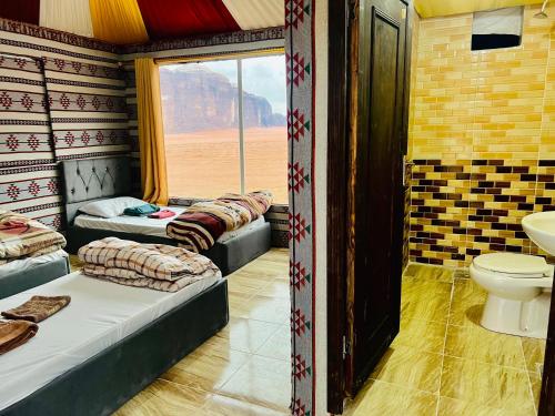 瓦迪拉姆Wadi Rum Cave Camp &Jeep Tour的客房设有三张床、卫生间和窗户。