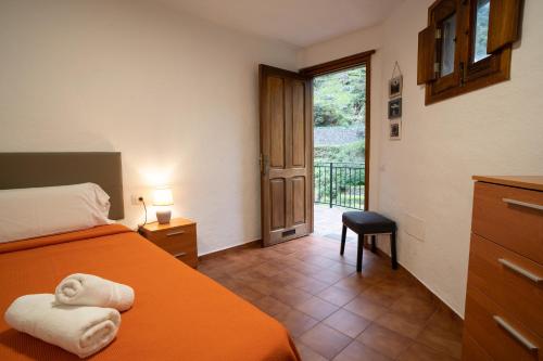 埃尔米瓜Casa Rural El Mantillo的一间卧室设有一张床,并有通往阳台的门