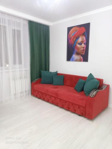 科克舍套Мухтара Ауэзова 205的客厅里一张红色的沙发,上面有绘画作品