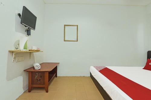 瓜埠OYO 90324 Muar Station Hotel的客房设有一张床和一张桌子及电视