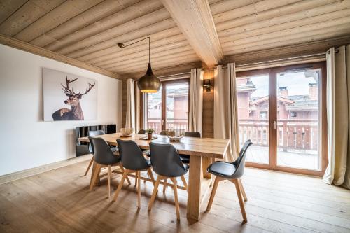 谷雪维尔Apartment Cervino Monriond Courchevel - by EMERALD STAY的一间带木桌和椅子的用餐室