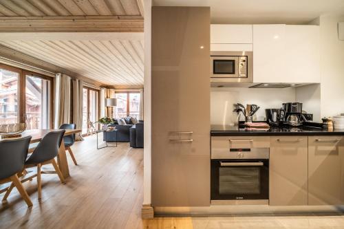 谷雪维尔Apartment Cervino Monriond Courchevel - by EMERALD STAY的厨房以及带桌椅的起居室。