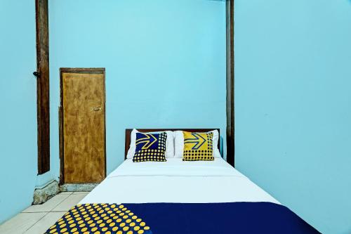 日惹SPOT ON 91916 Joglo Doyong Homestay Syariah的蓝色客房,配有带枕头的床