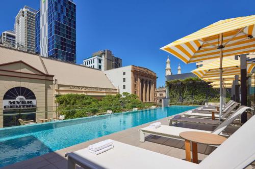 布里斯班Hyatt Regency Brisbane的大楼内带桌子和遮阳伞的游泳池