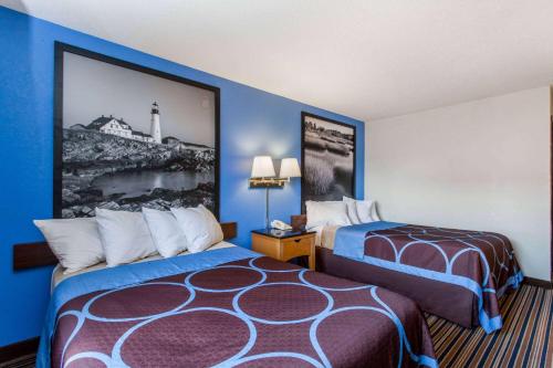 刘易斯顿路易斯顿奥本区速8酒店的酒店客房设有两张床,墙上挂着一张照片。