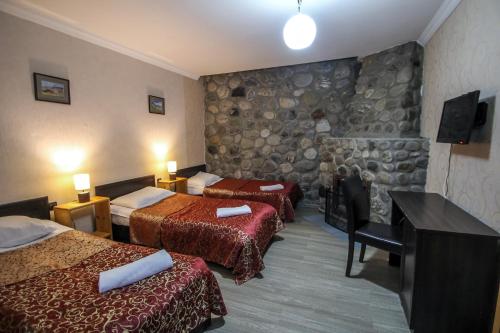梅斯蒂亚Hotel Svaneti的酒店客房设有两张床和石墙。