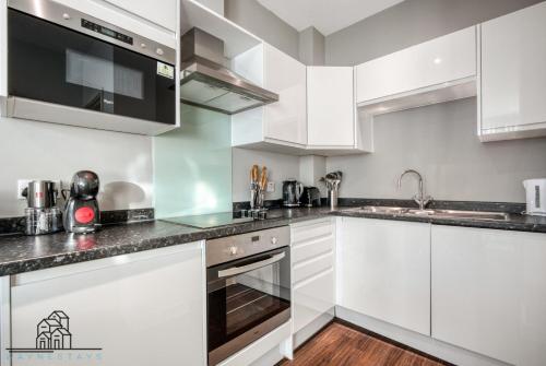 伦敦Cosy 1-Bed by Heathrow Airport的厨房配有白色橱柜和不锈钢用具