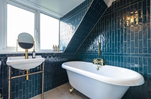 浦耳The Anchorage的蓝色瓷砖浴室设有浴缸和水槽