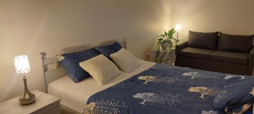 考纳斯Pakeliui的一间卧室配有一张带蓝色床单的床和一张沙发