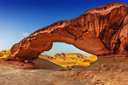 瓦迪拉姆Sunset Mountain的沙漠中的岩石拱,下面有一条路