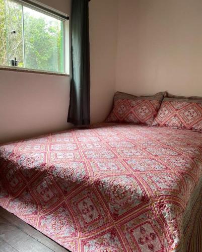 韦尔卡鲍Micro casa com vista para o Morrão - Vale do Capão的一间卧室配有一张带红色棉被的床和窗户。